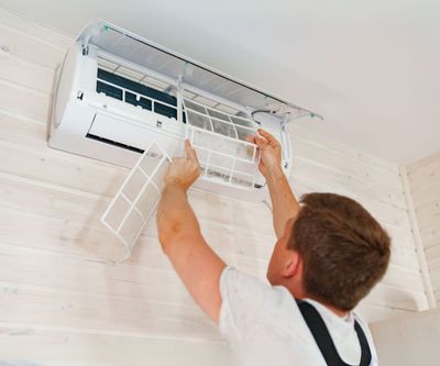 A man is cleaning the filter of an air conditioner.