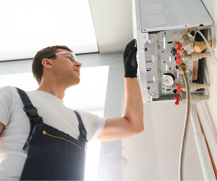 A man in overalls is working on an air conditioner