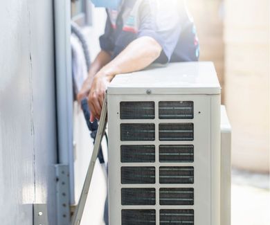 A man is installing an air conditioner on the side of a building.