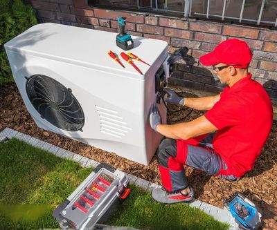 A man in a red shirt is working on an air conditioner.