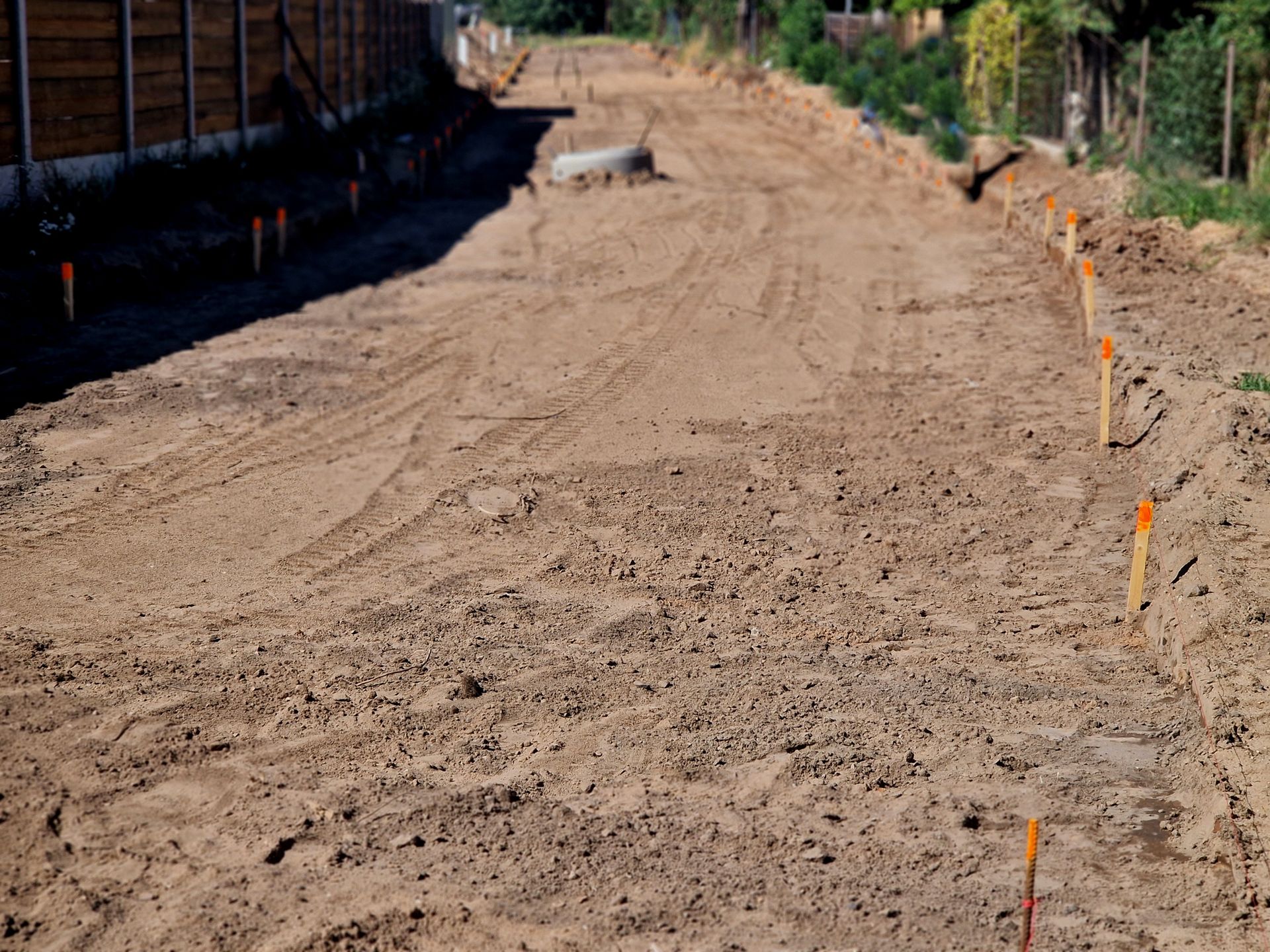 A dirt road with orange markers on the side of it.