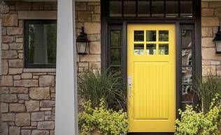 A yellow door is on the front of a brick house.
