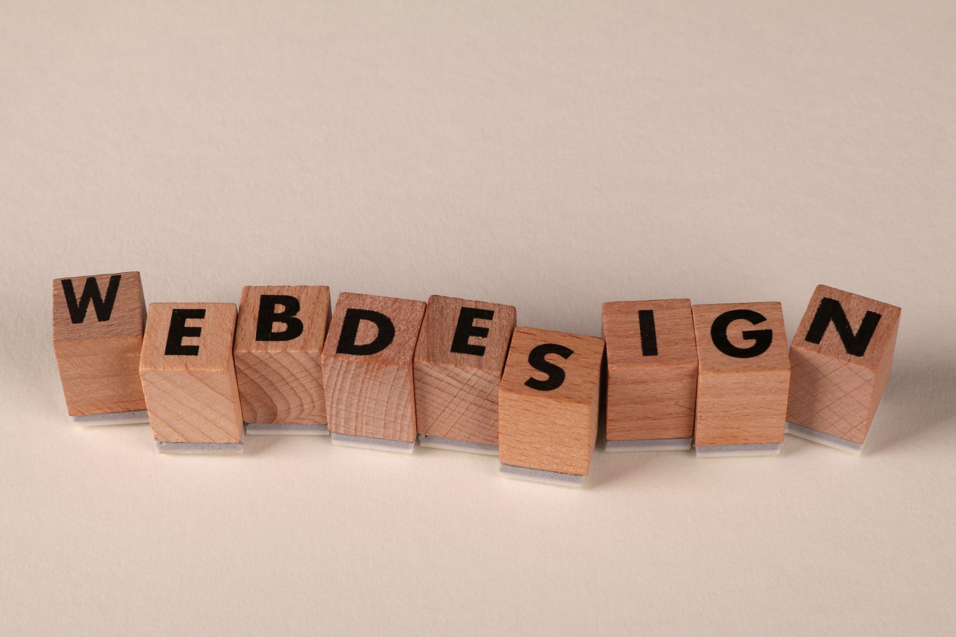 Wooden blocks spelling “WEB DESIGN” on a beige background