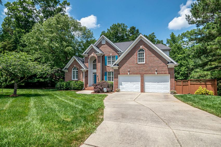 A large brick house with a driveway leading to it is for sale.