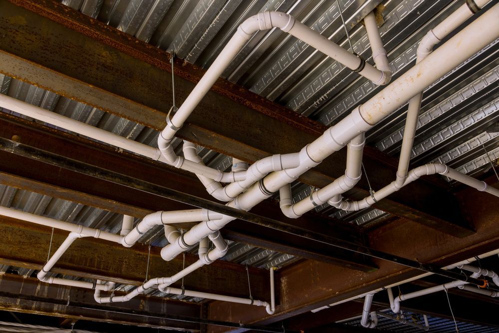White Pipes Zig-zag Across a Ceiling With Metal Beams — Sunset Plumbing NT in Moil, NT