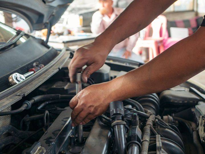 A man is working on the engine of a car with a wrench.