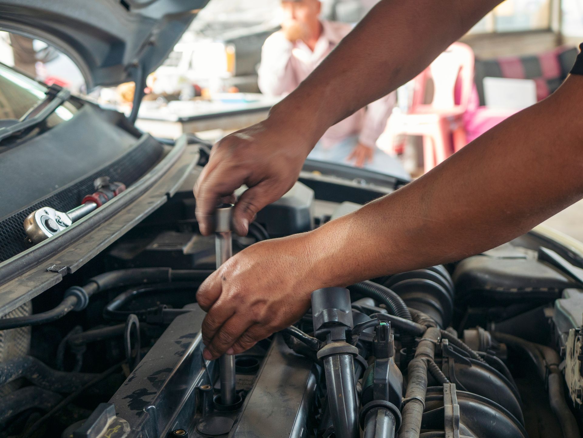 A man is working on the engine of a car with a wrench.