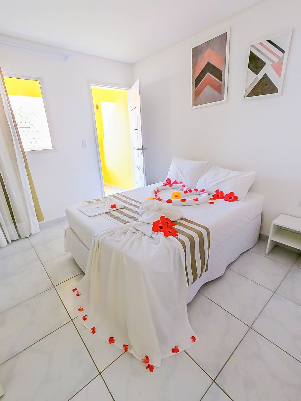 Um quarto com uma cama decorada com flores e uma porta amarela.