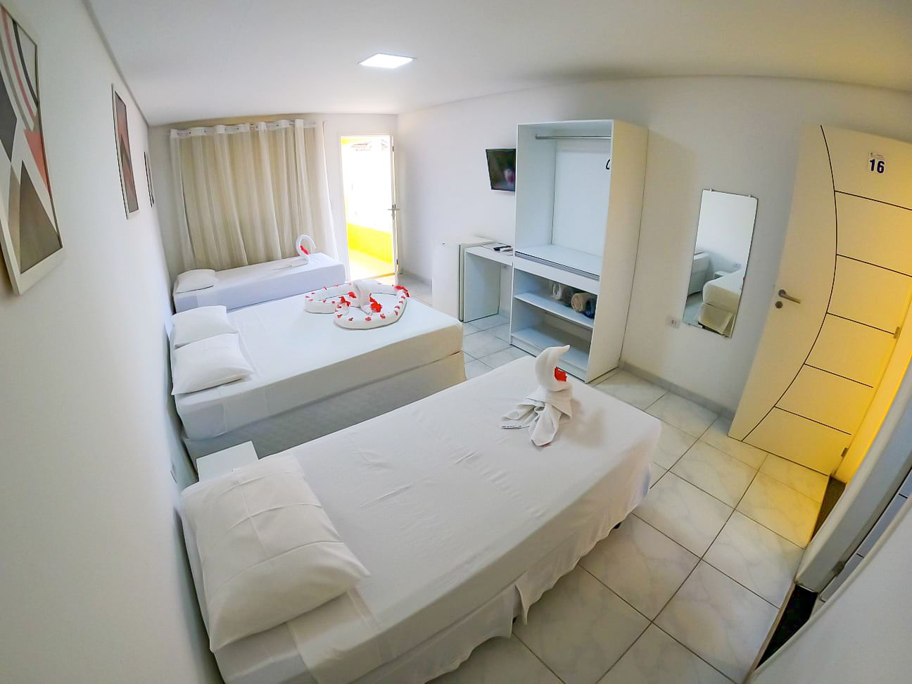 Um quarto de hotel com três camas e um espelho