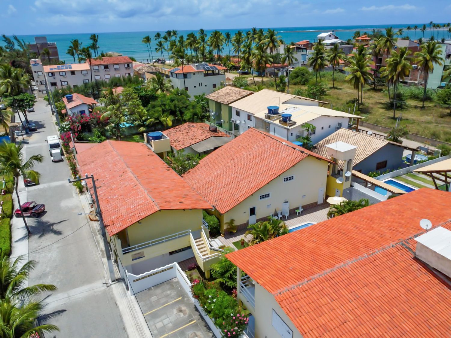 Uma vista aérea de uma área residencial com casas e palmeiras perto do oceano.