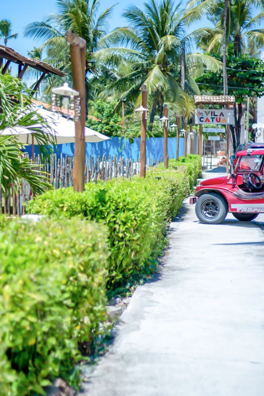 Um carro vermelho está estacionado na beira de uma estrada ao lado de uma placa.