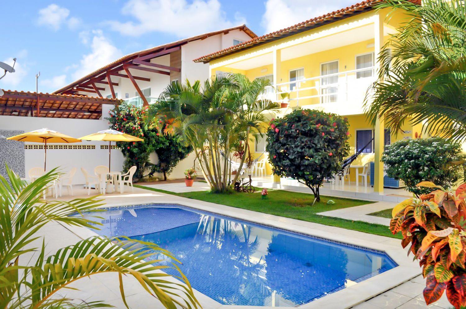 Uma grande piscina em frente a uma casa amarela