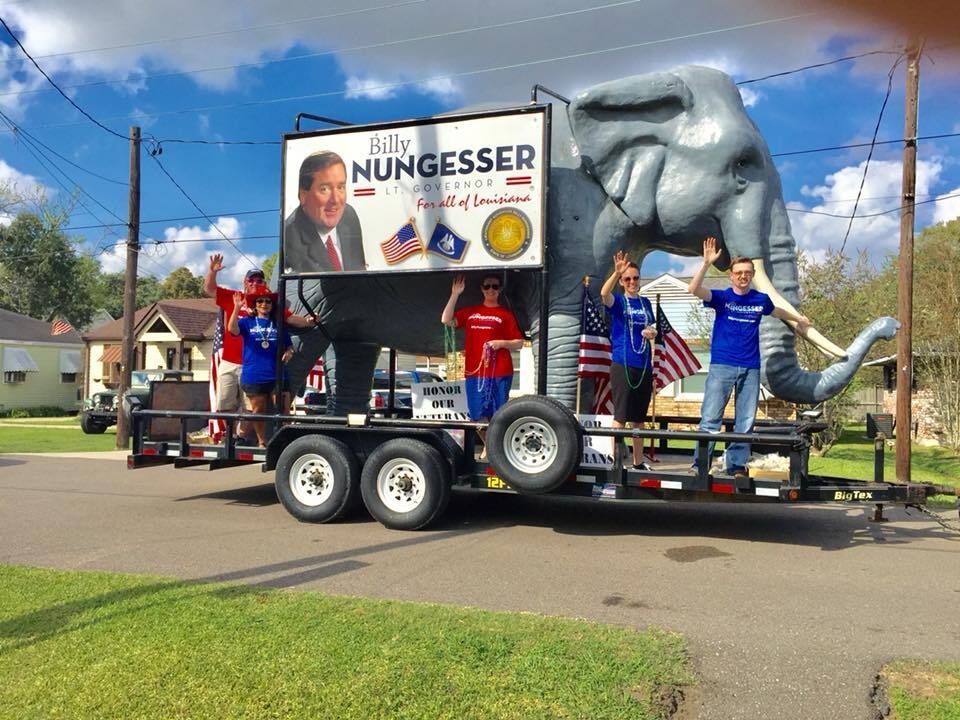 A group of people are standing on a trailer with an elephant on it.