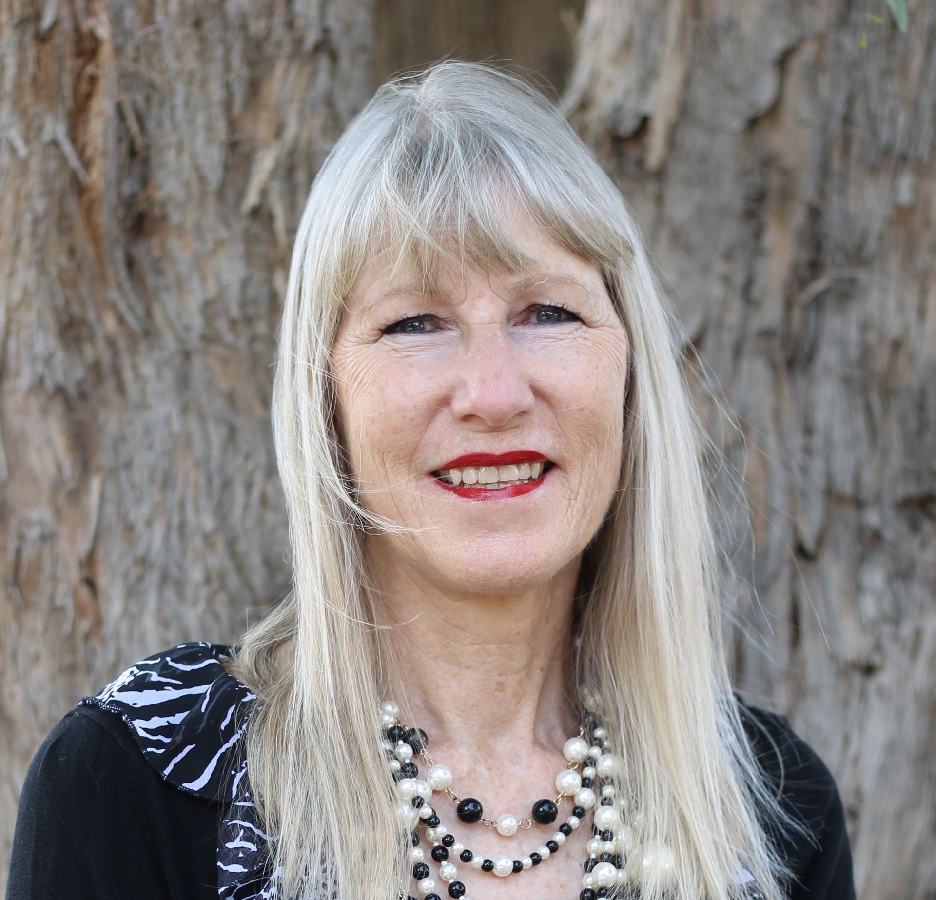A woman wearing a red jacket and scarf is smiling for the camera.