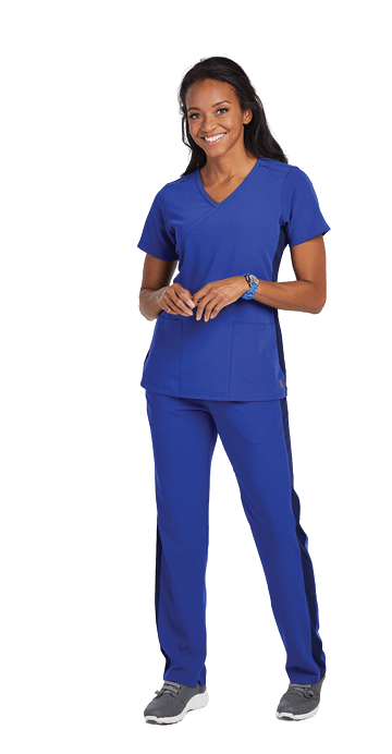 A woman wearing a blue scrub top and pants is standing on a white background.