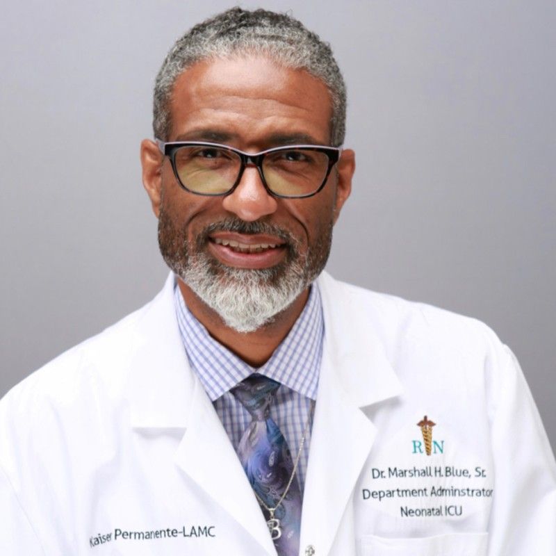 A man with glasses and a beard is wearing a lab coat and tie