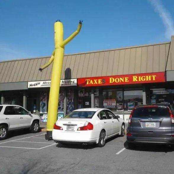 A yellow inflatable tube man dances outside a business named 