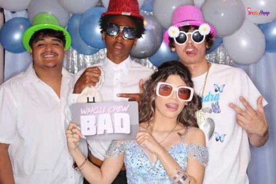 A group of friends posing with props in a birthday party photo booth.