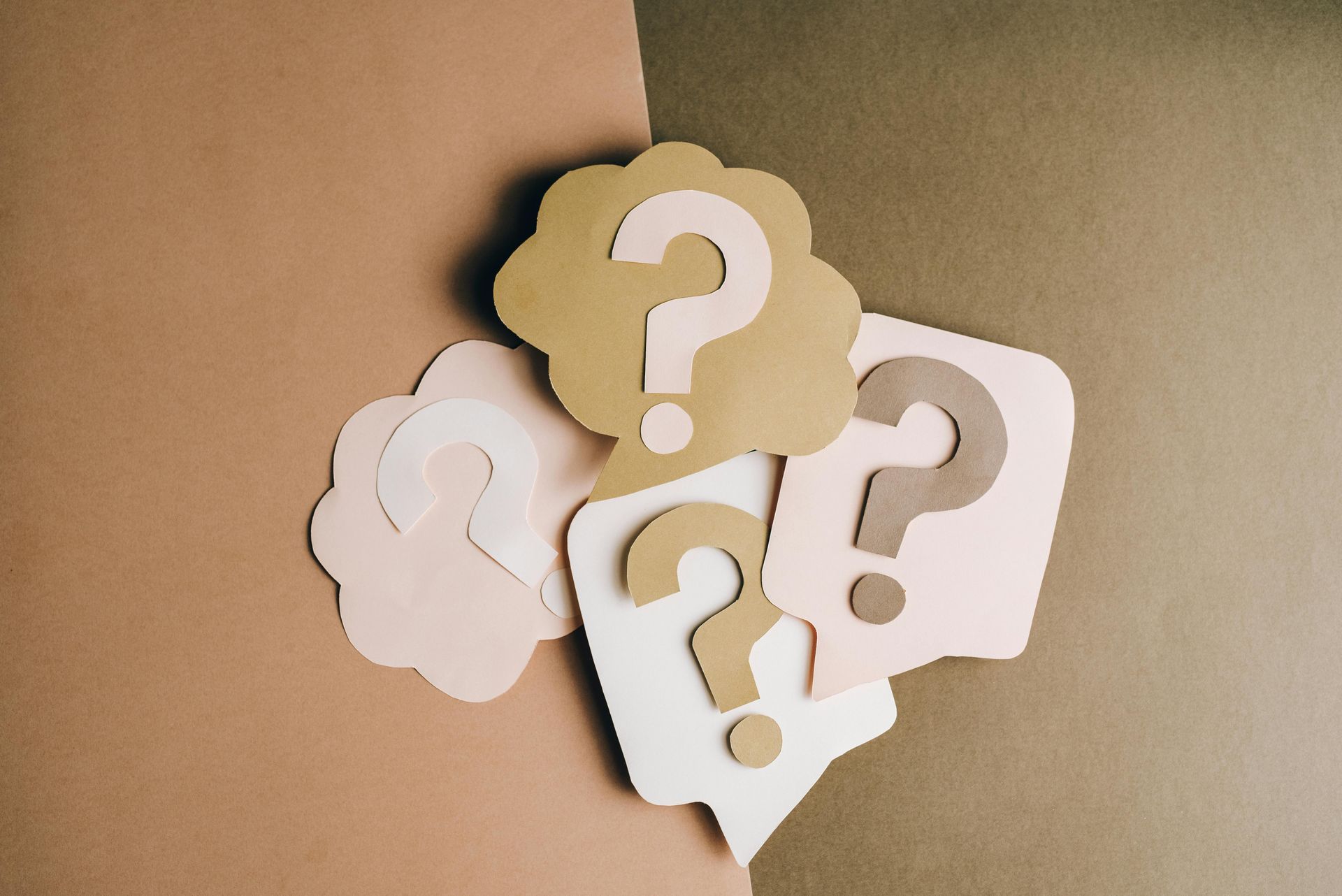 Paper question marks inside speech bubbles on brown backgrounds.