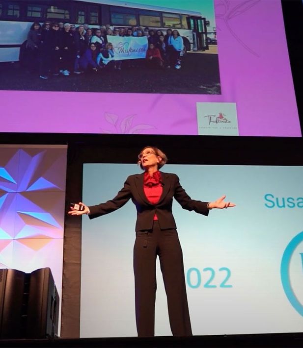 A woman stands in front of a screen that says susan 022