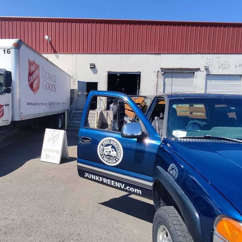 A blue truck is parked in front of a salvation army truck
