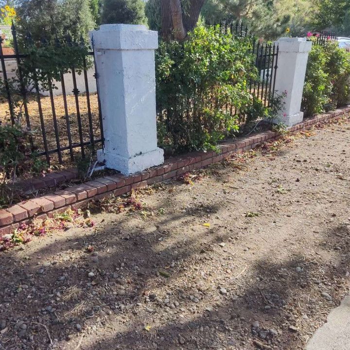 A fence with white pillars and a brick border