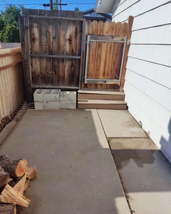 A backyard with a wooden fence and a pile of logs