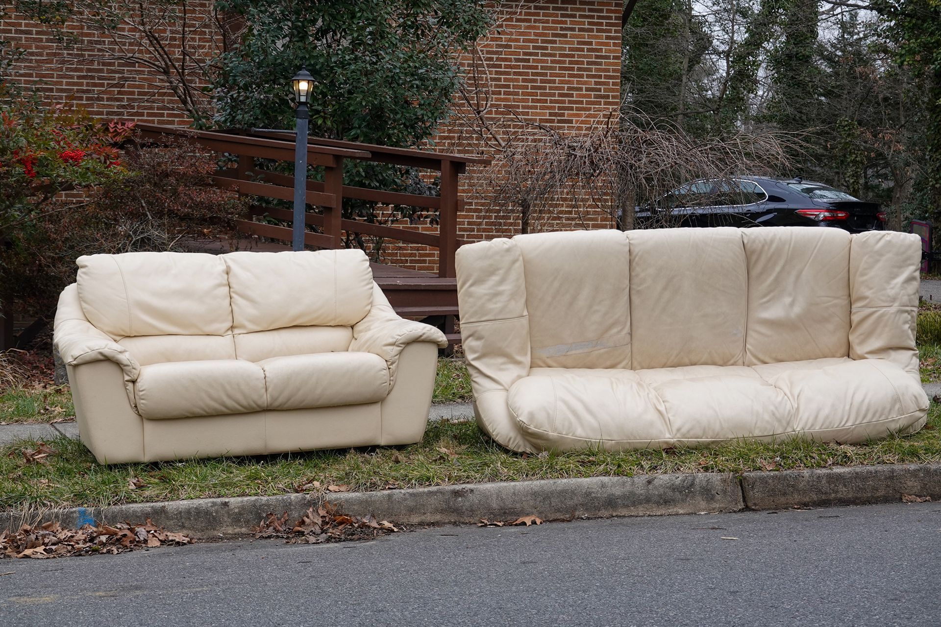 Two white leather couches are parked on the side of the road