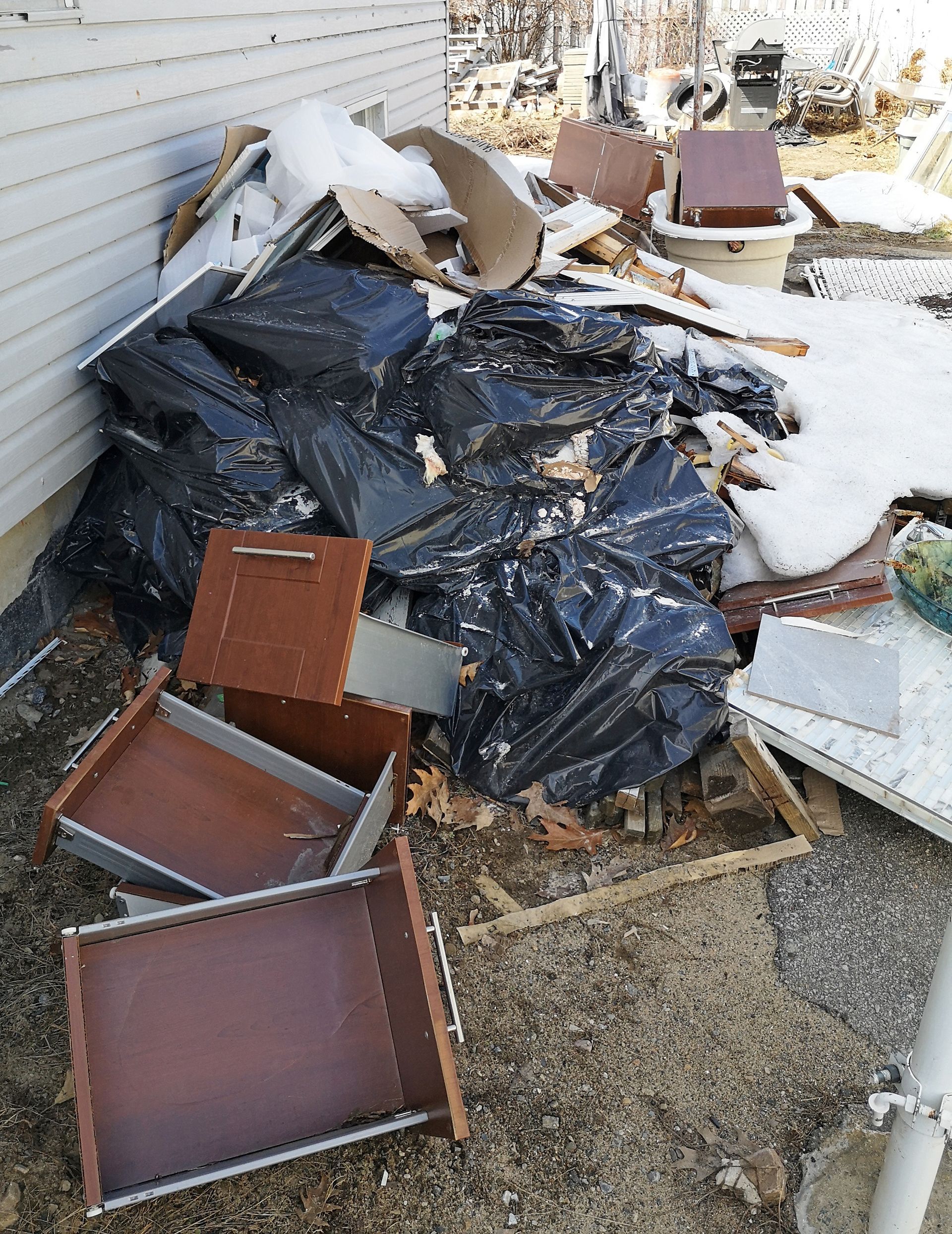 A pile of trash is sitting on the ground in front of a house.
