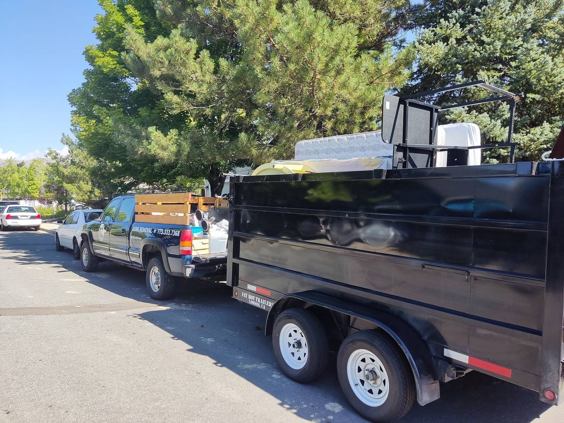 A truck is towing a dump trailer down a street.