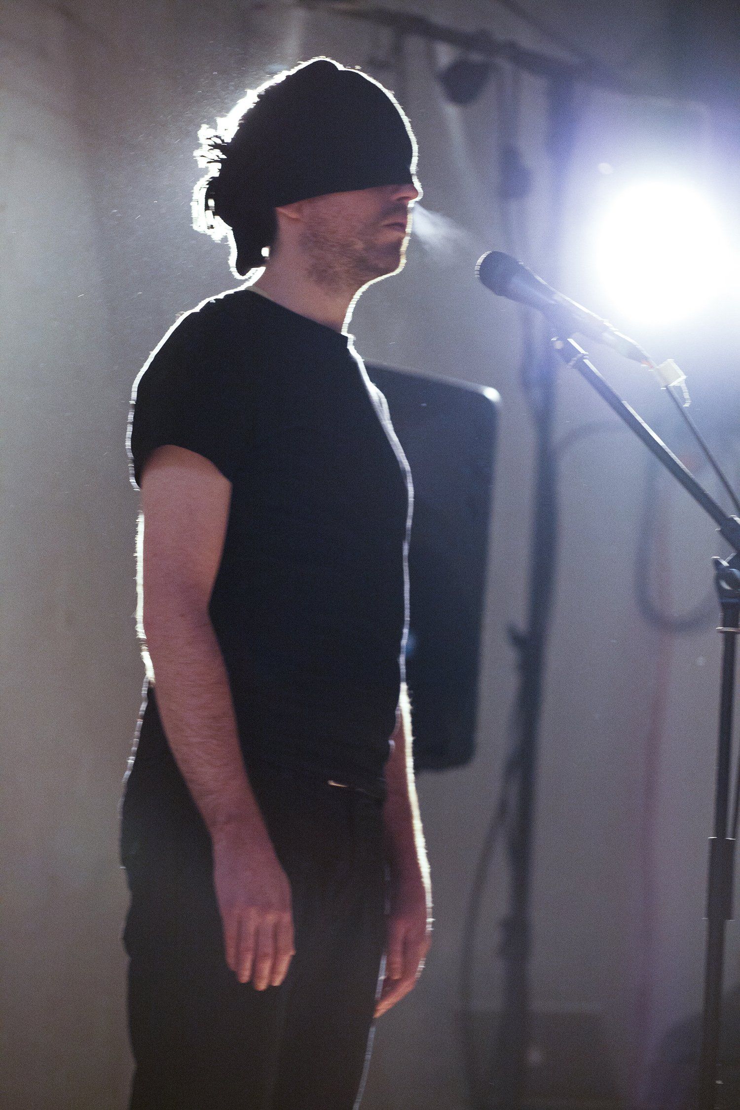 a man in a black shirt is standing in front of a microphone .