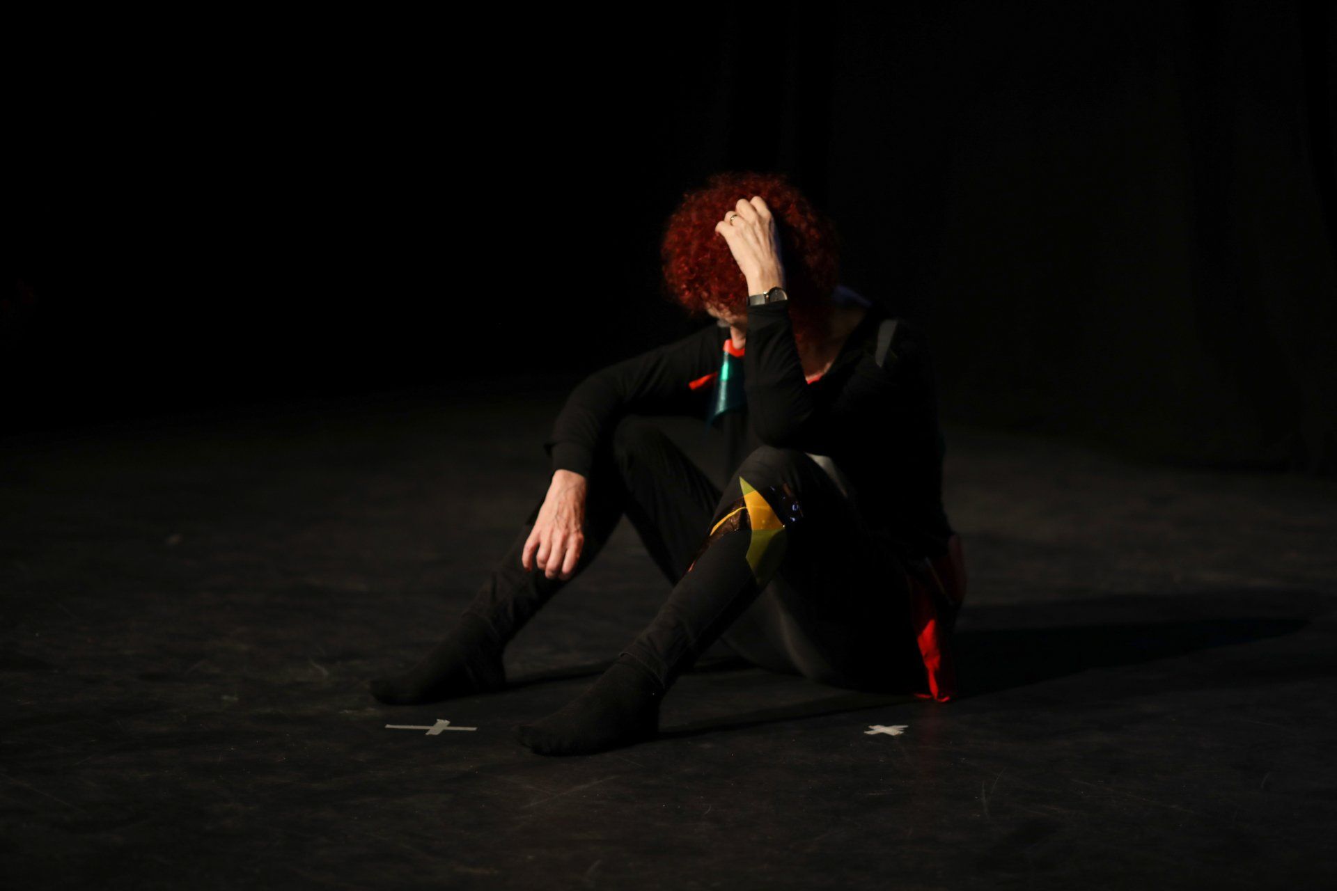 a woman with red hair is sitting on the floor with her head in her hands .