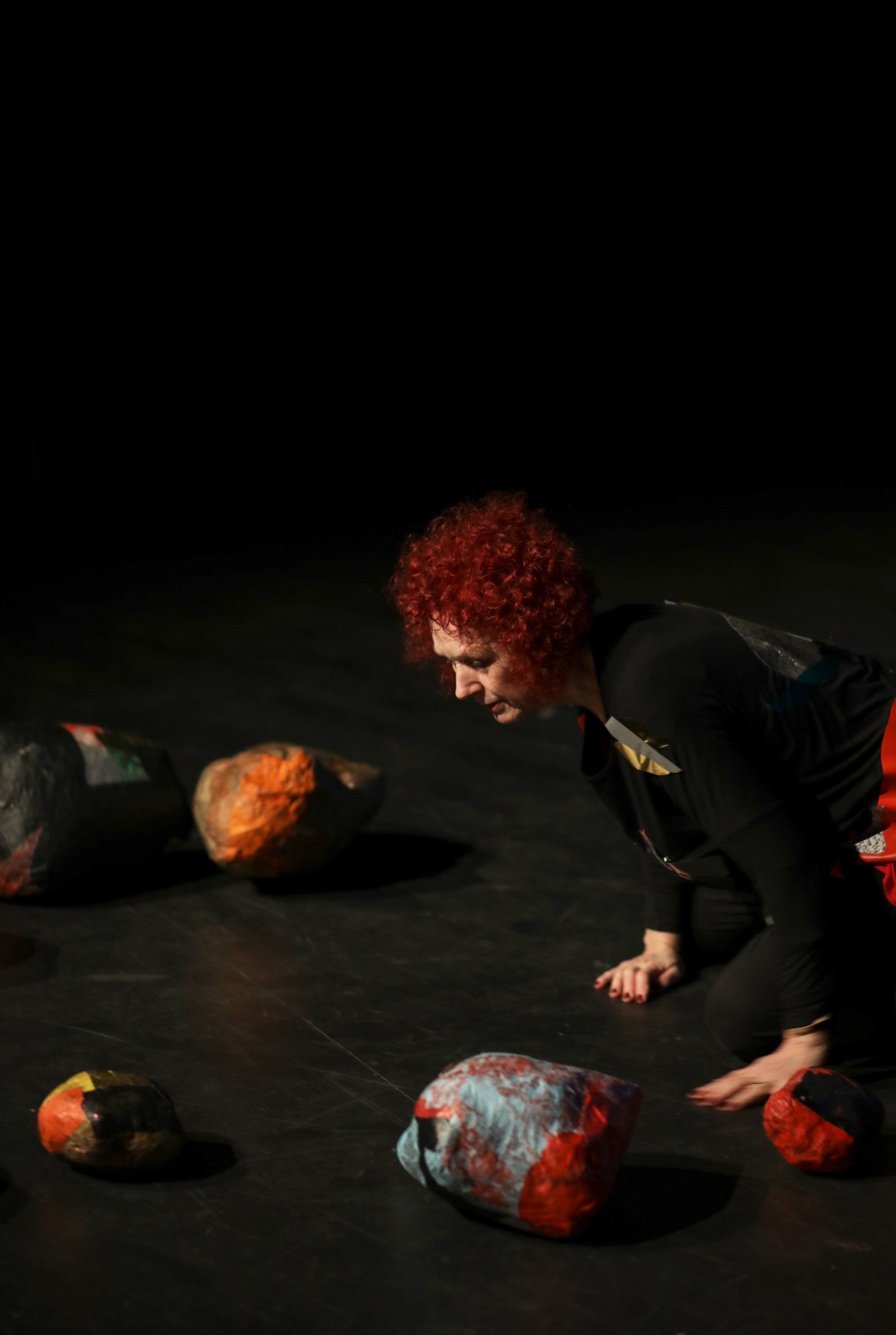 a woman with red hair is crawling on the floor next to a pile of rocks .