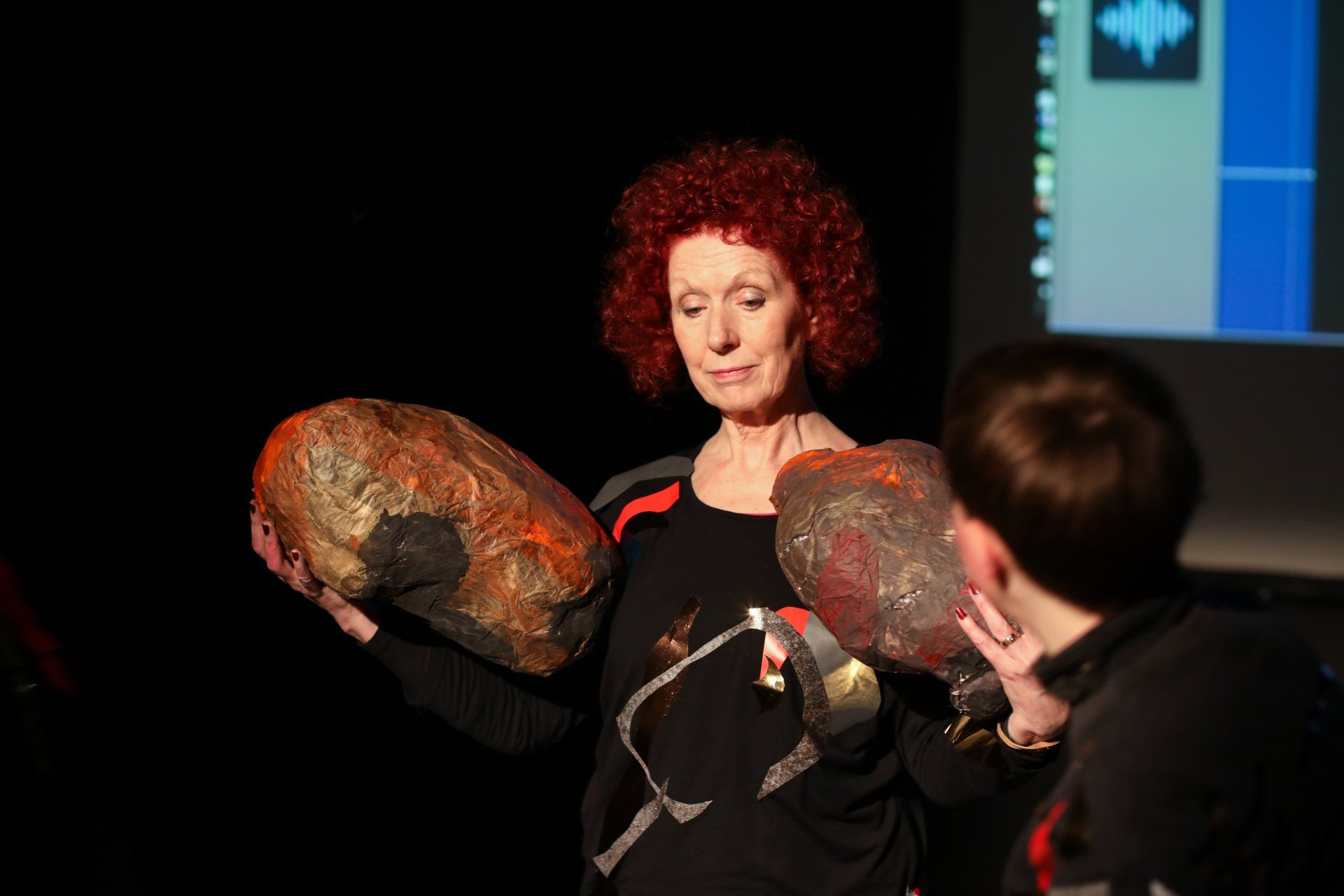 a woman with red hair is holding two large rocks in her hands .