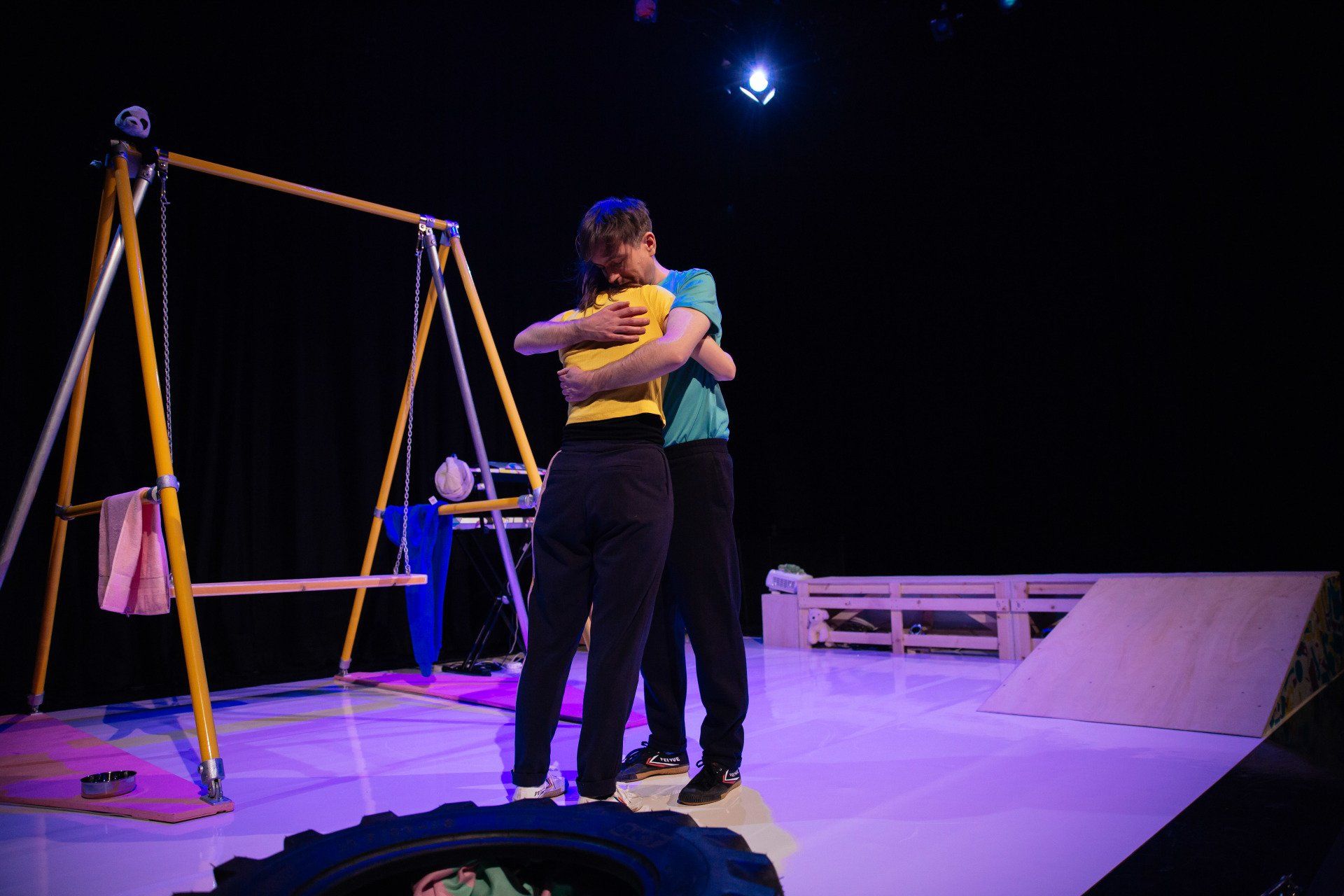 a man and a woman are hugging on a stage in front of a swing set .