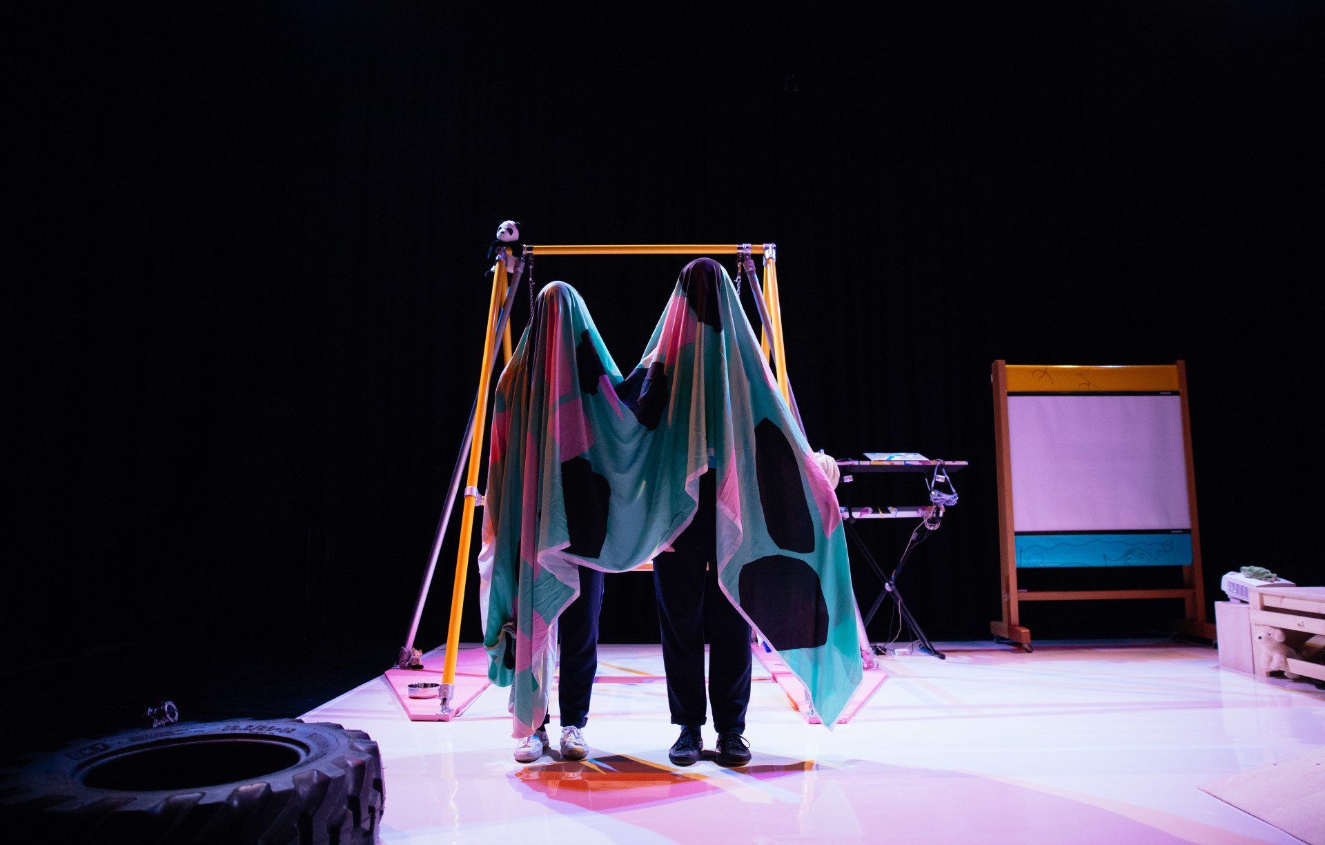 two people are standing on a stage with a colorful cloth covering their faces .