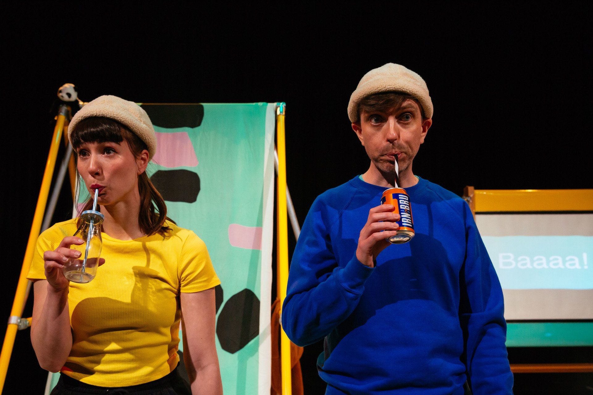 a man and a woman are drinking through straws on a stage .
