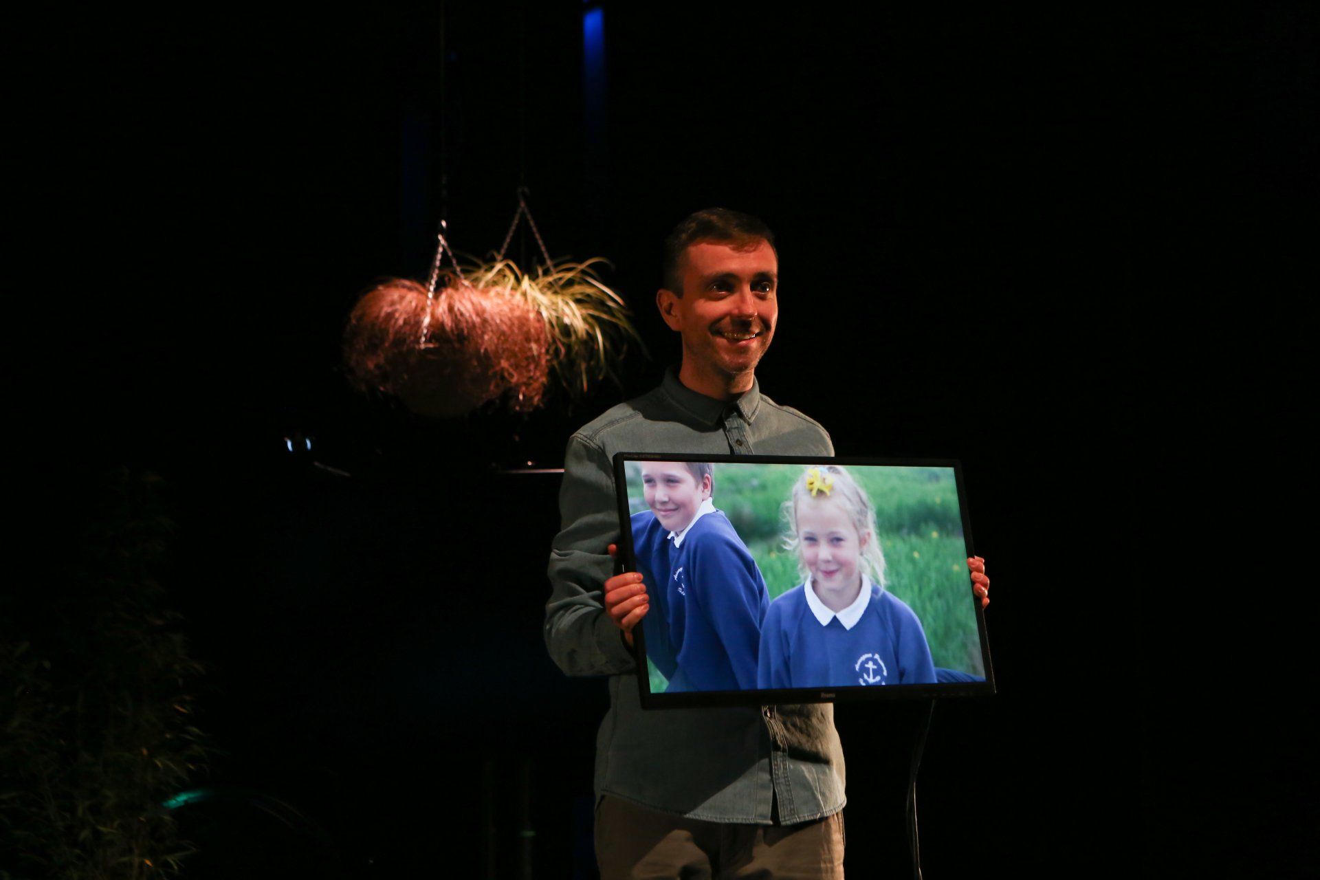 a man is holding a picture of two children on a screen .