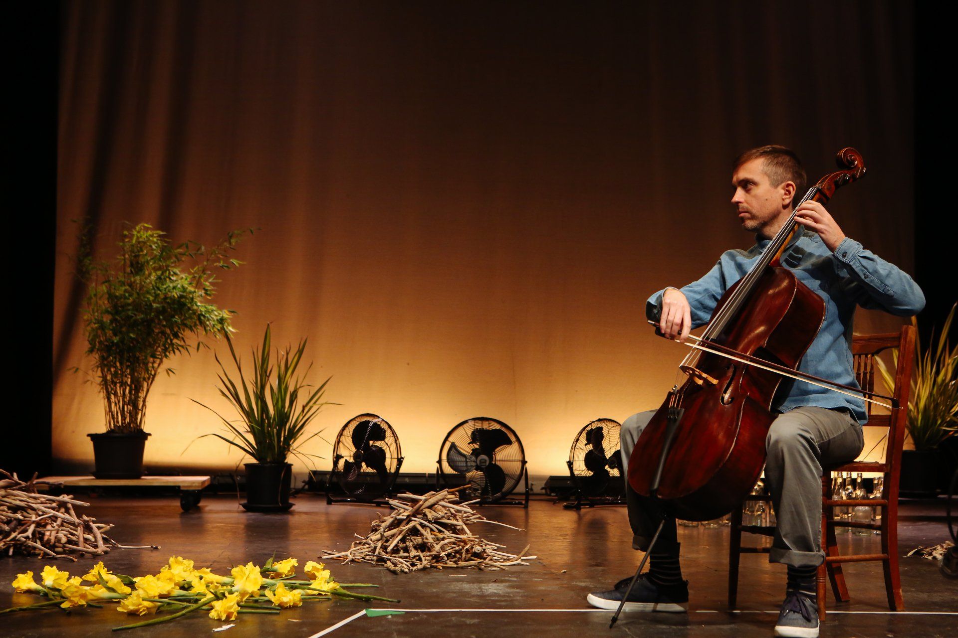 a man is sitting on a chair playing a cello on a stage .
