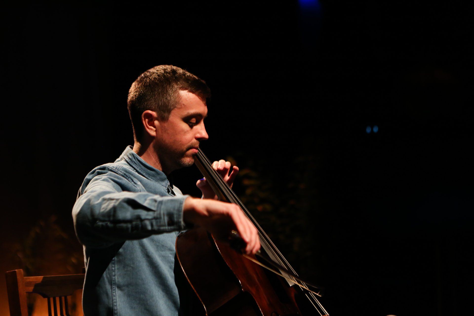 a man is playing a cello in a dark room .