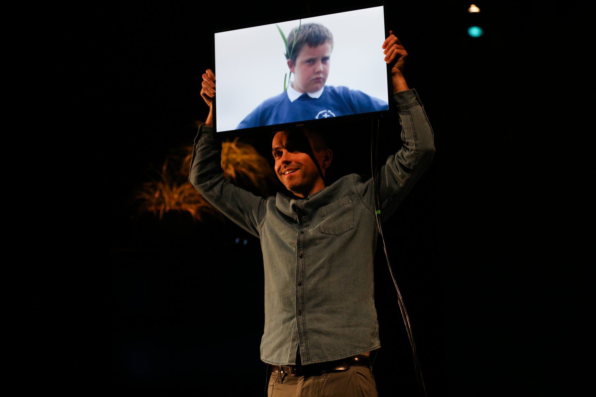 a man is holding up a picture of a child on a screen .