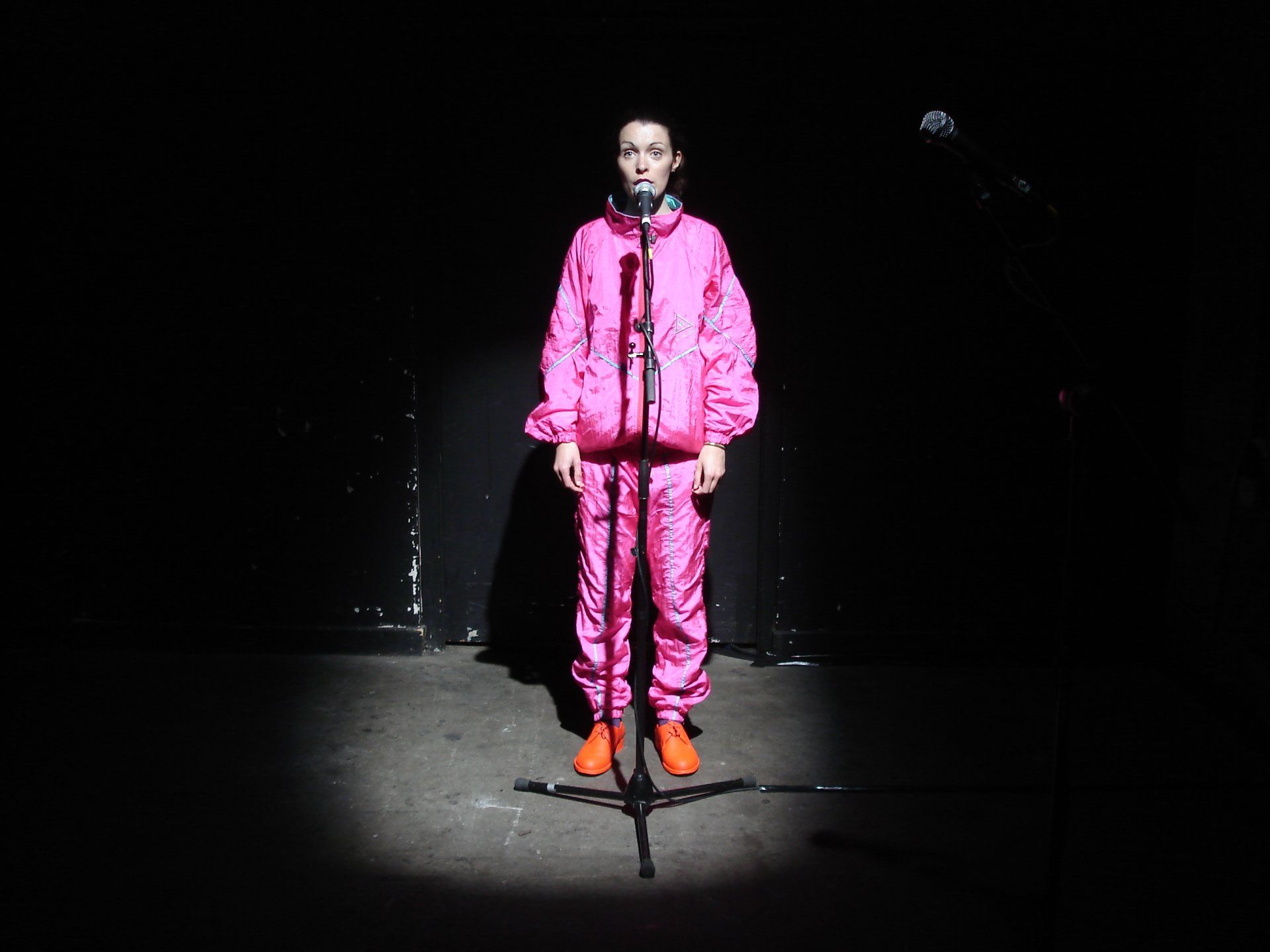 a person in a pink suit is standing in front of a microphone .