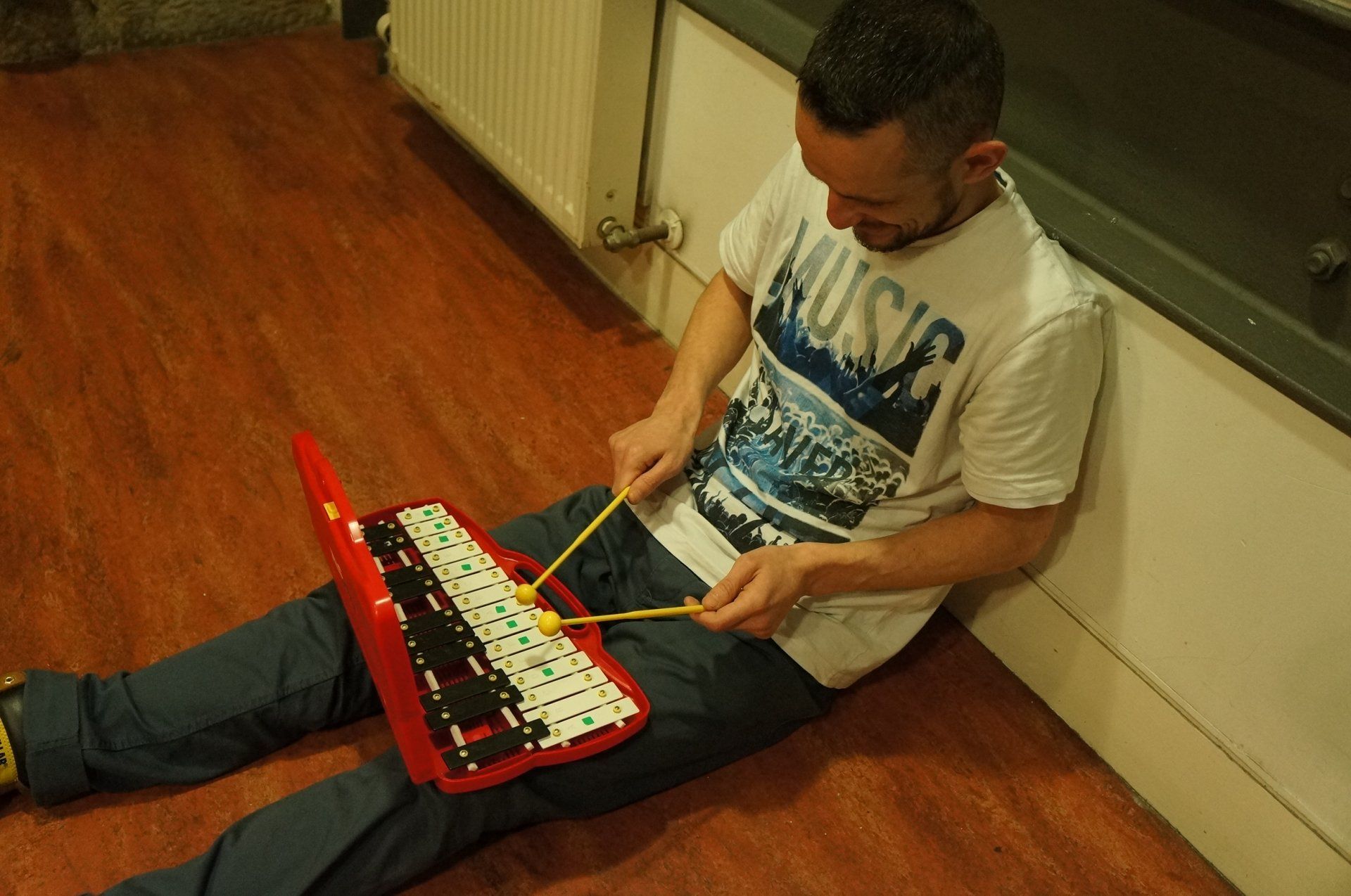a man is sitting on the floor playing a toy keyboard .