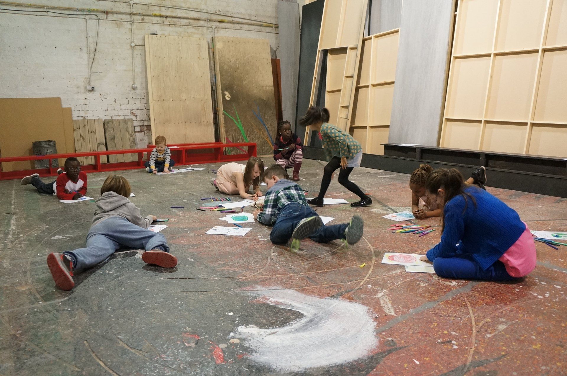 a group of children are laying on the floor drawing
