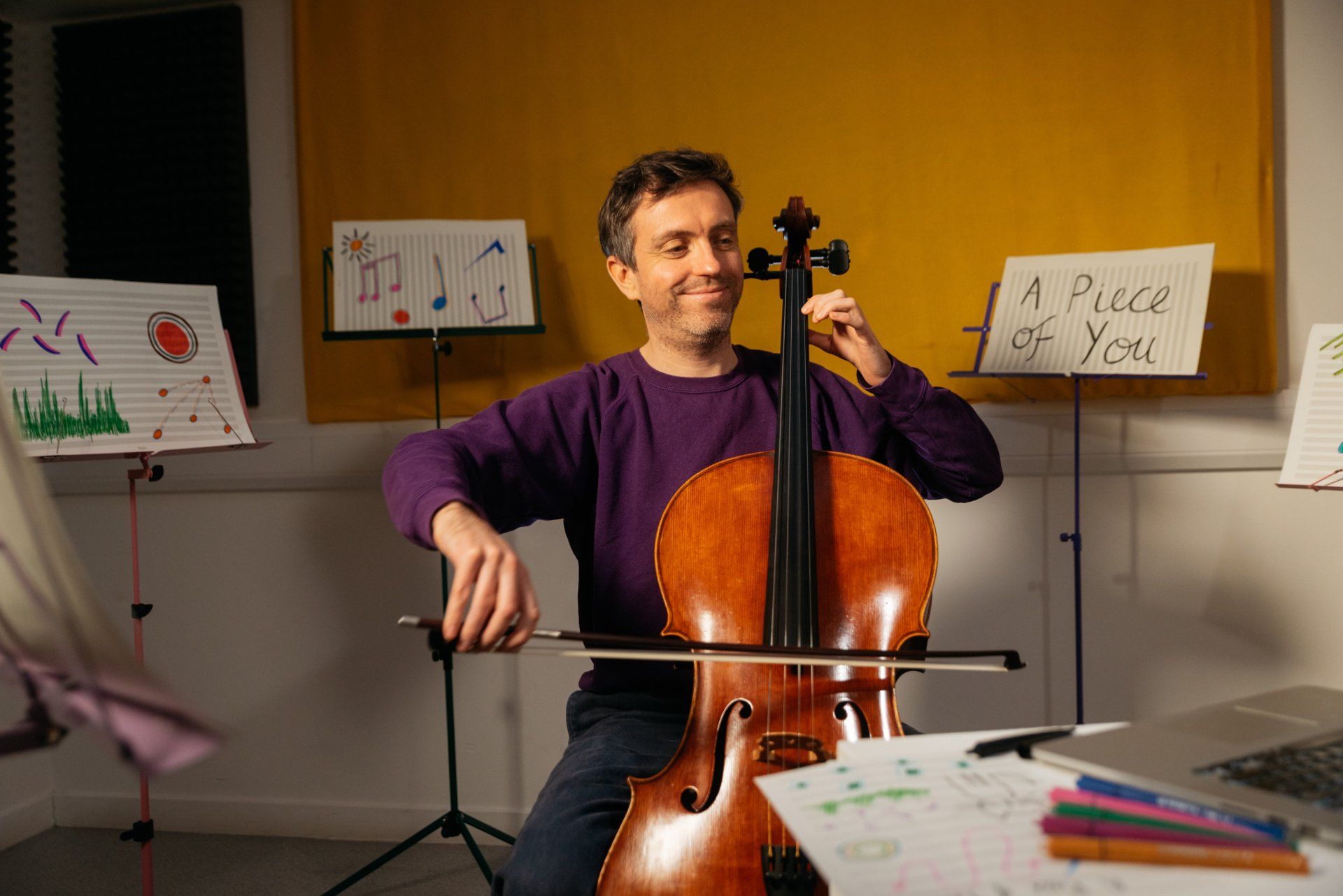 a man in a purple sweater is playing a cello .