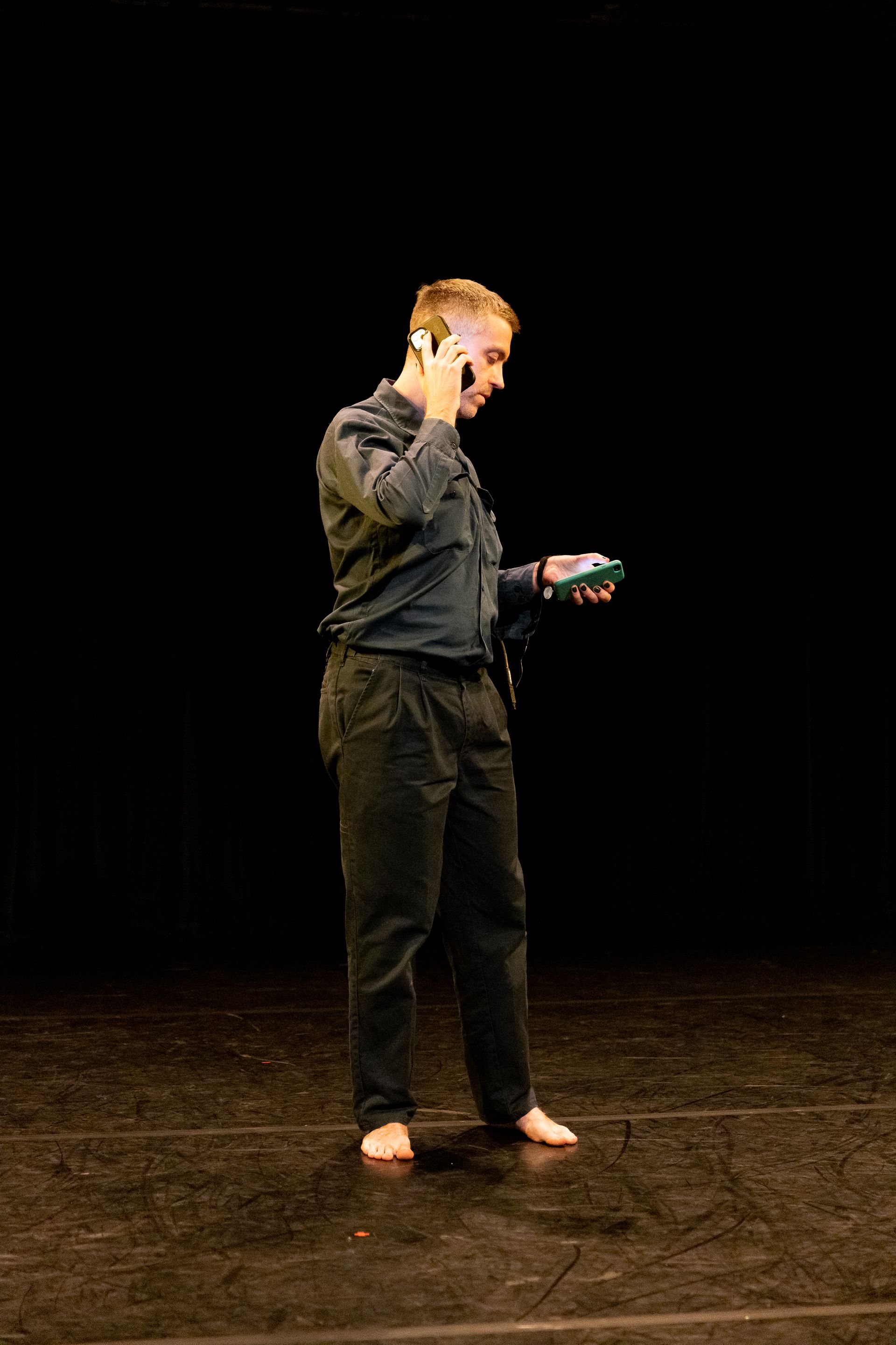 A man is standing on a stage talking on a cell phone.