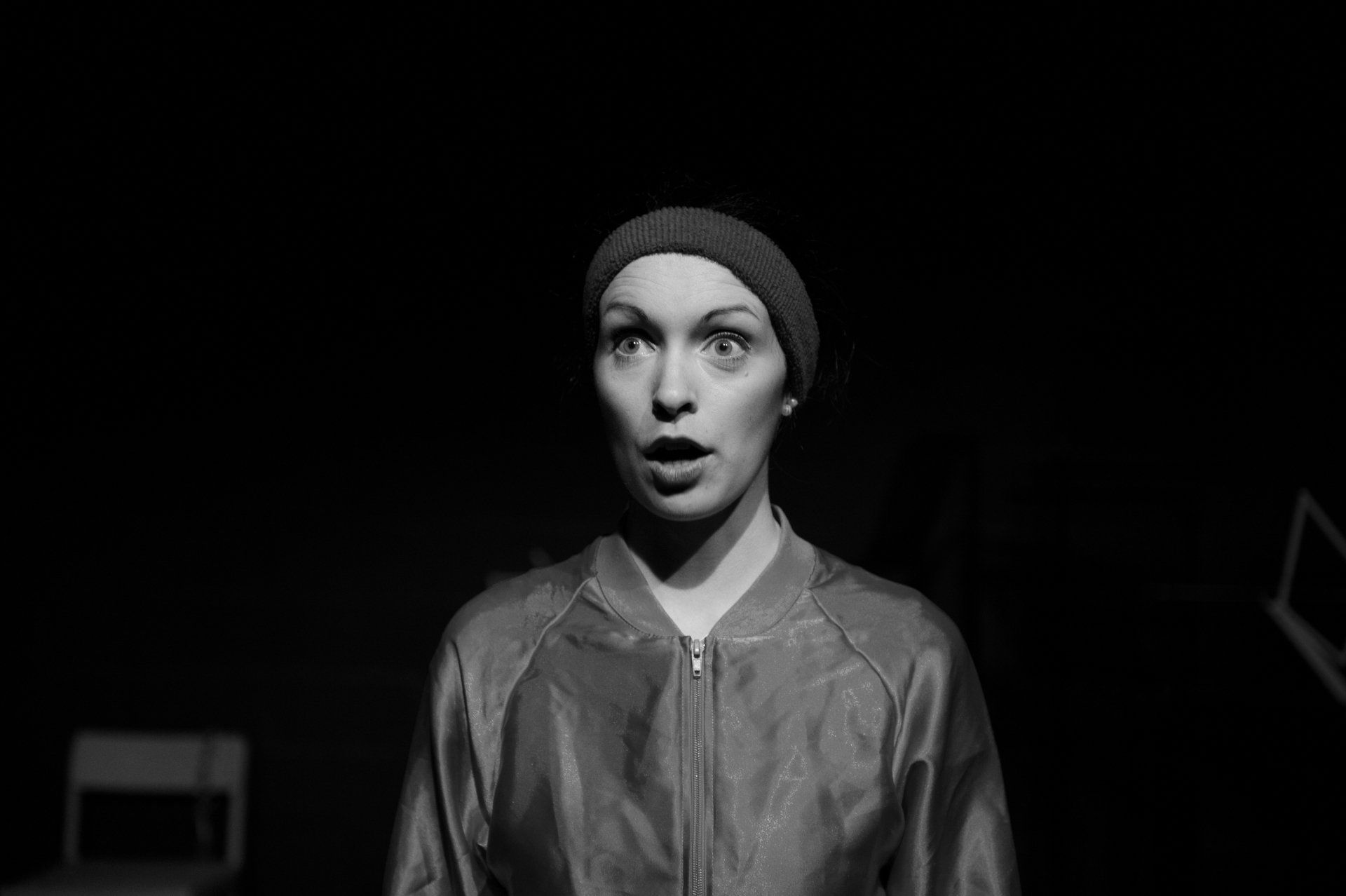 a black and white photo of a woman wearing a beanie and a leather jacket .