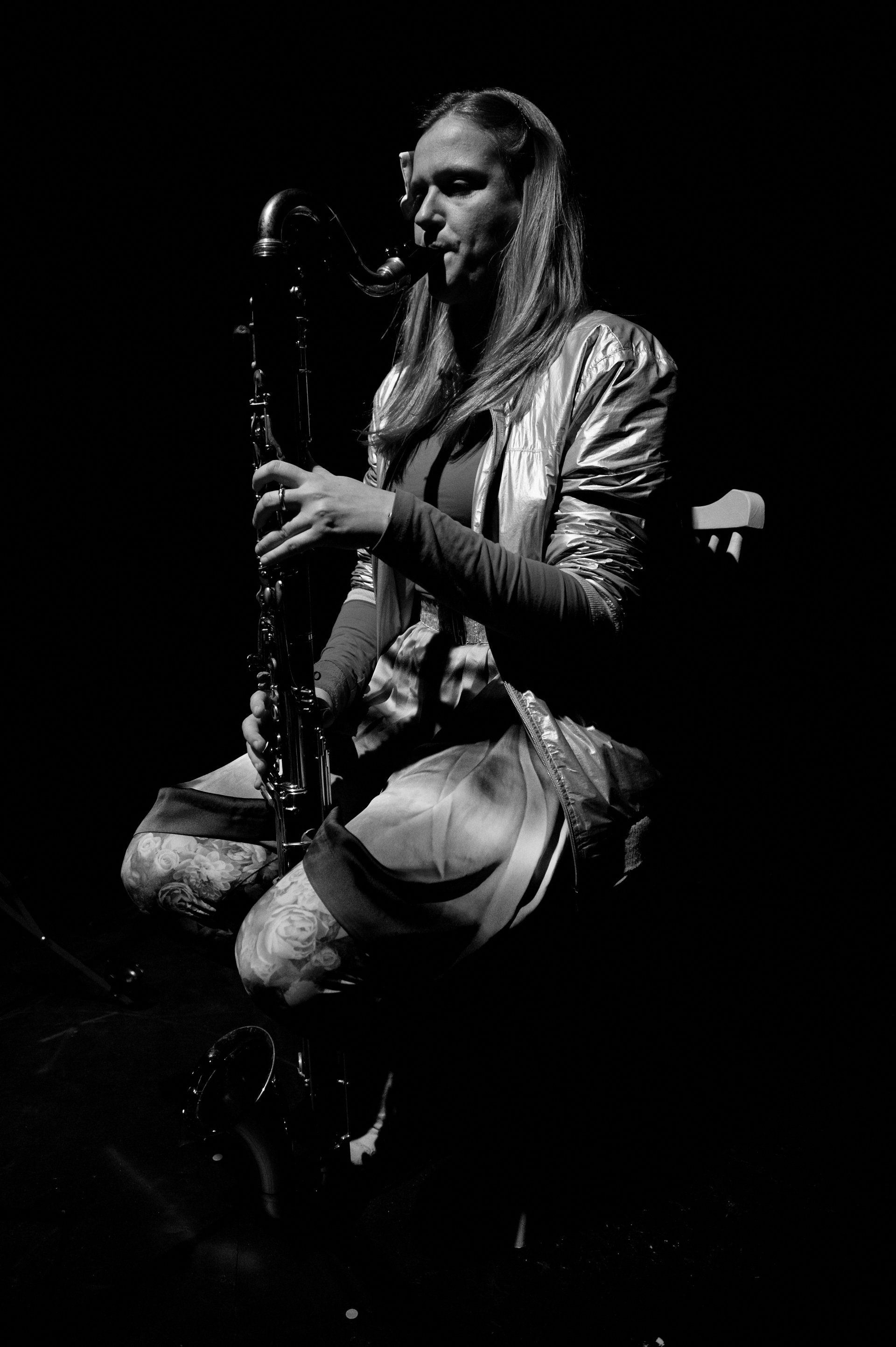 a woman is playing a saxophone in a black and white photo .