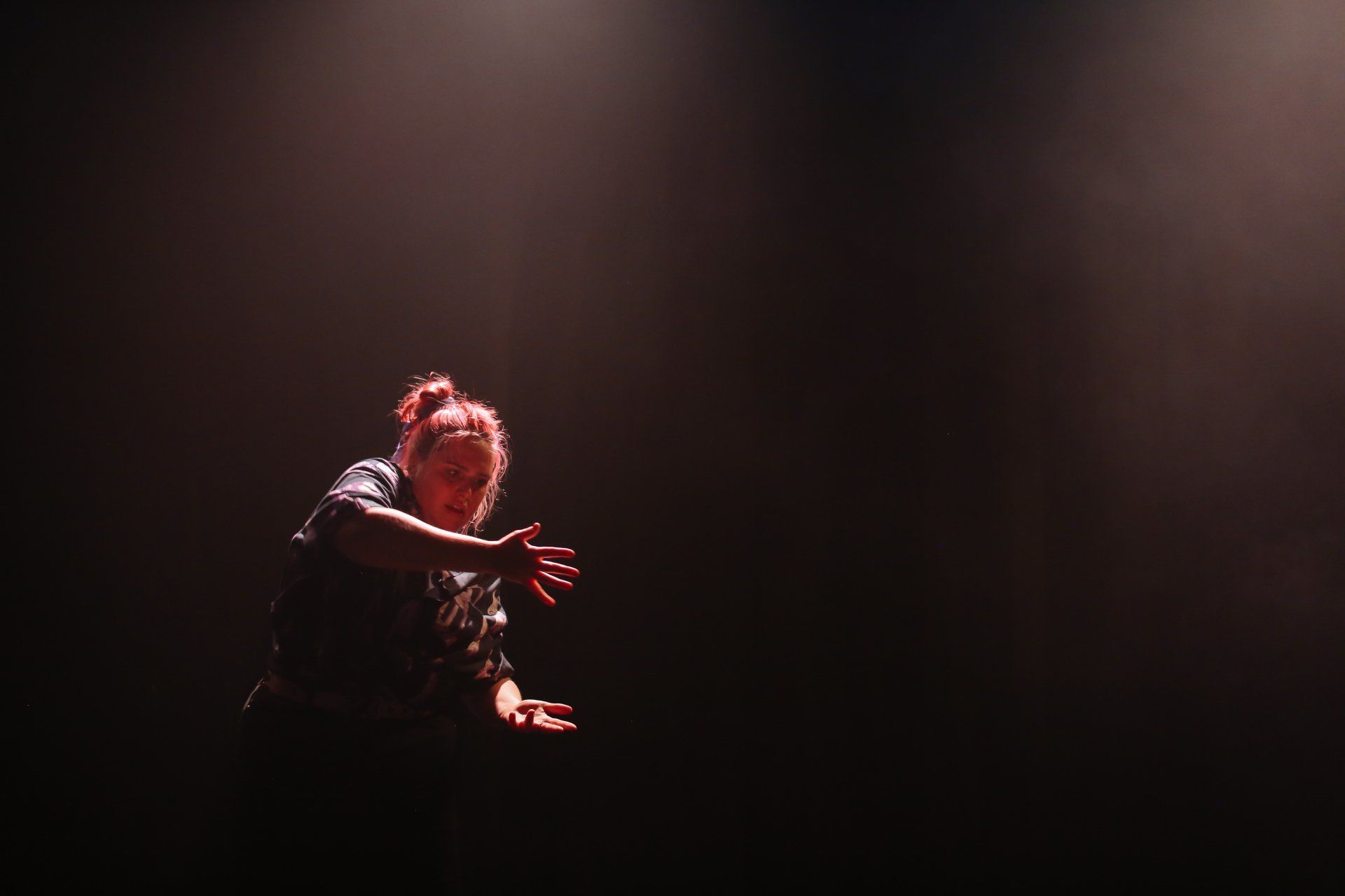 a woman is dancing on a stage in a dark room .