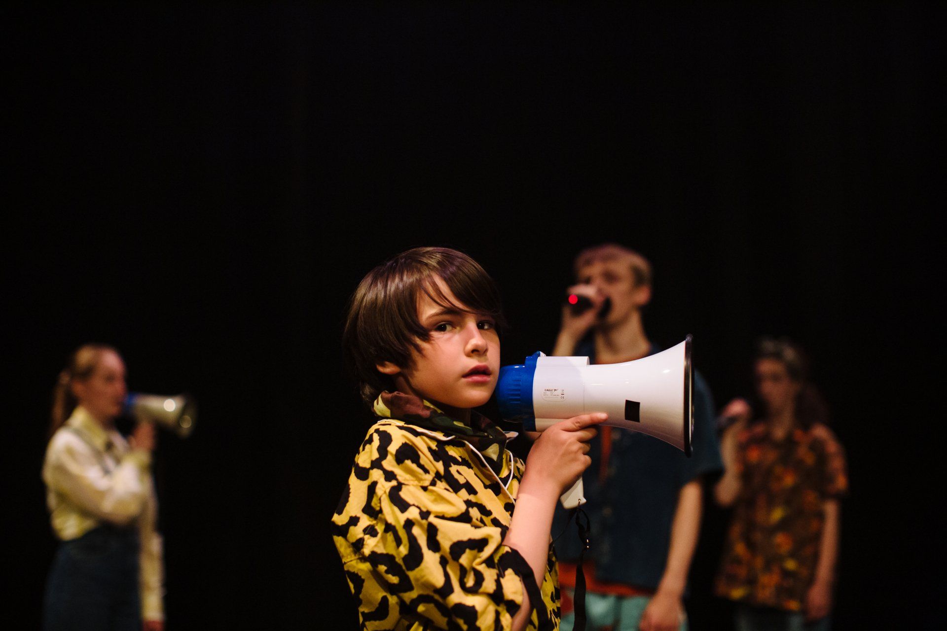 a young boy is holding a megaphone in a dark room .